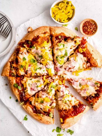 overhead image of sliced bbq chicken pizza on white table