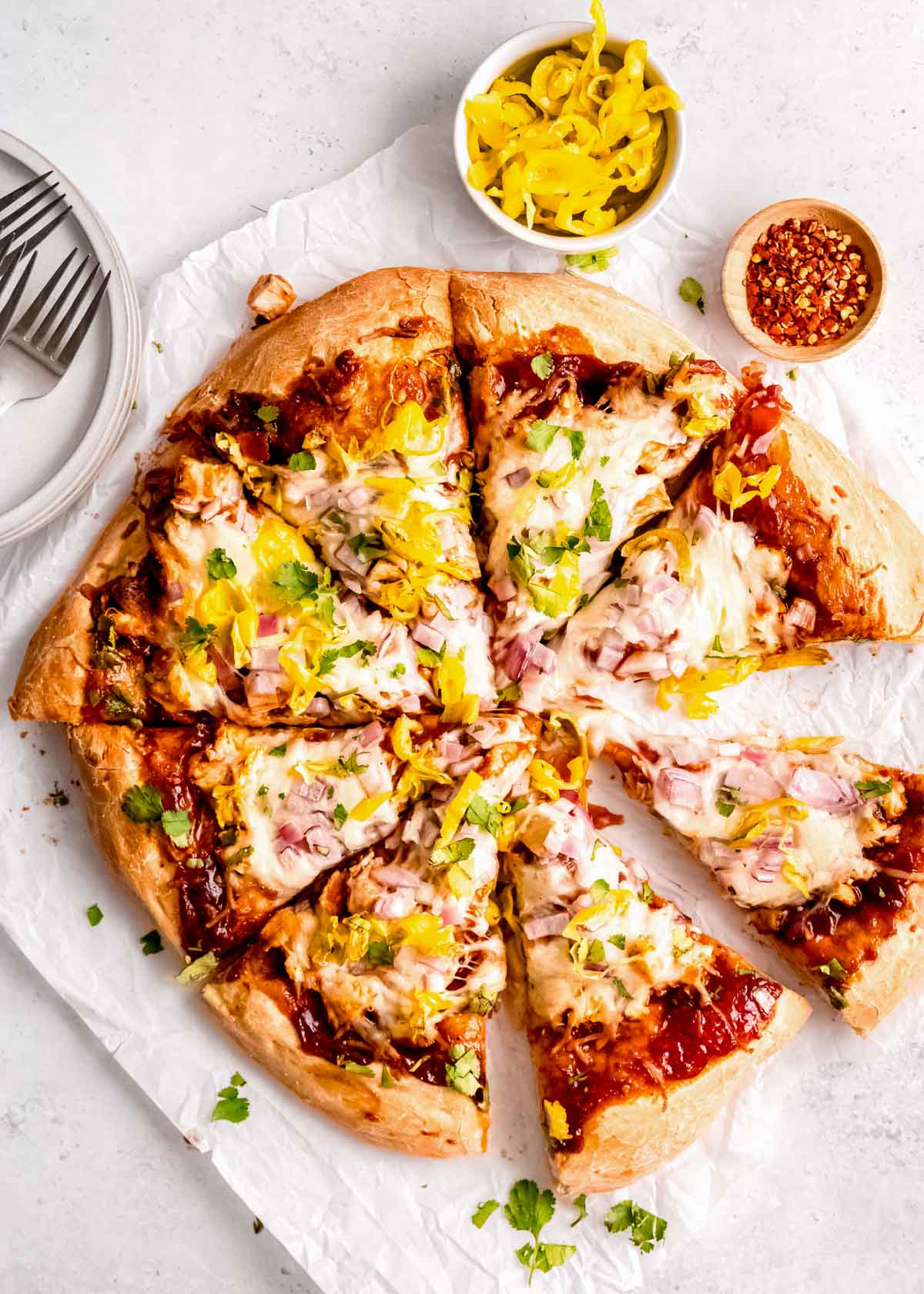 overhead image of sliced bbq chicken pizza on white table