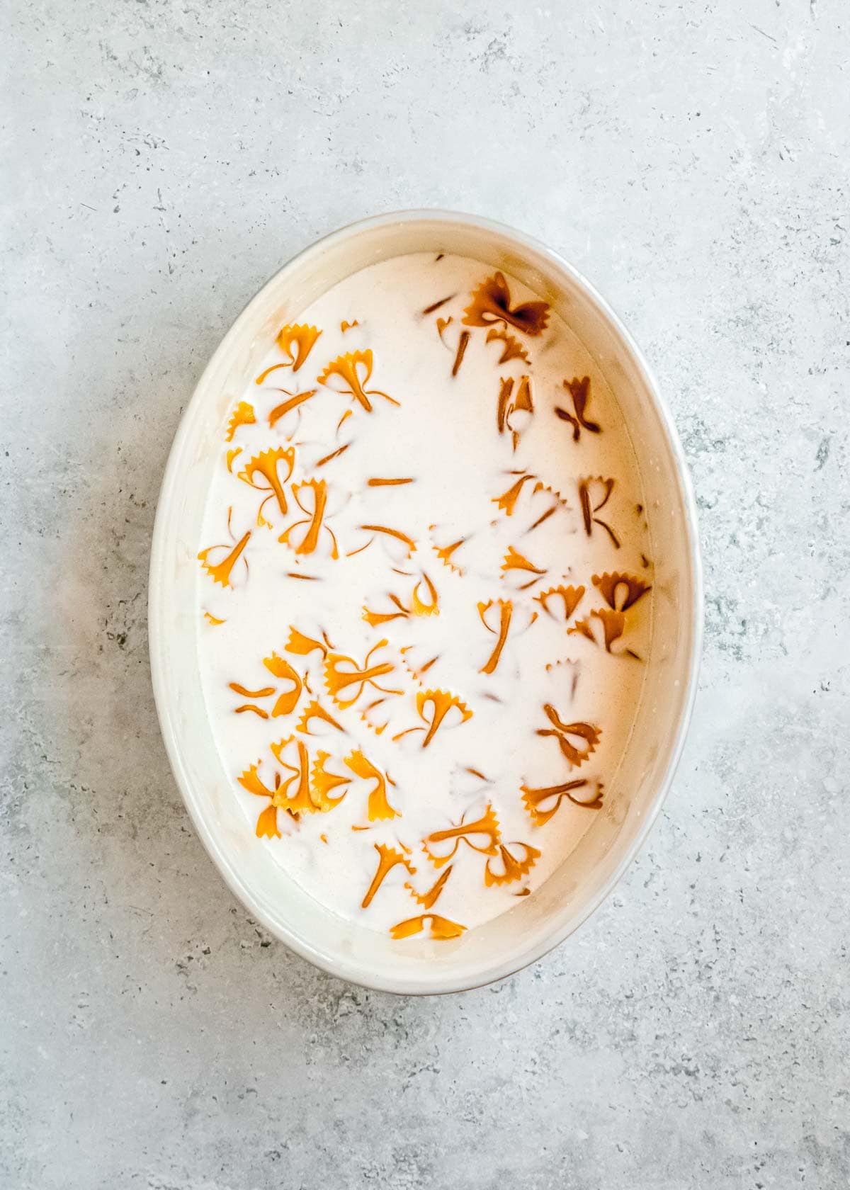 pasta being added to sauce in baking dish