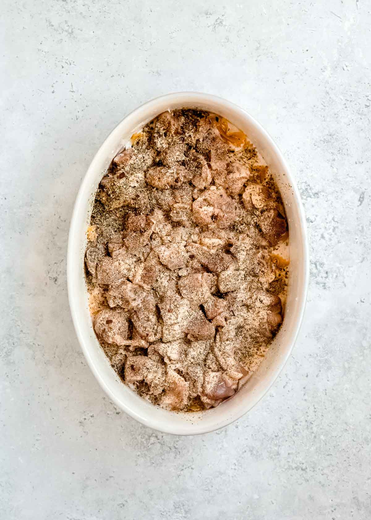 spices being added to baking dish with other ingredients 