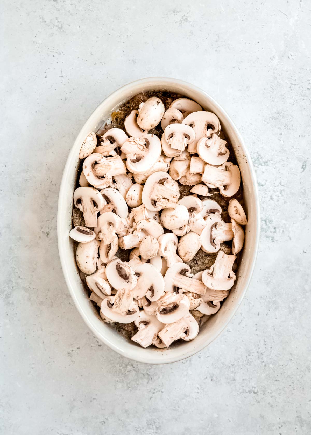 overhead image of mushrooms being added to baked chicken and mushroom pasta 