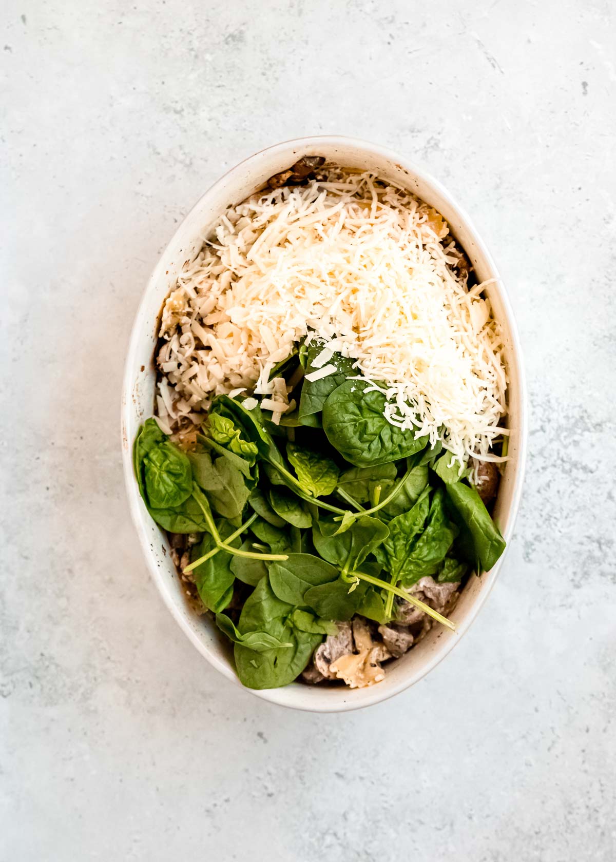 overhead image of mozzarella and spinach being added to chicken and mushroom pasta