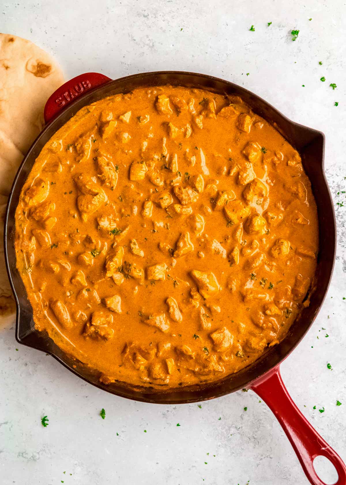 overhead image of cooked butter chicken in red skillet