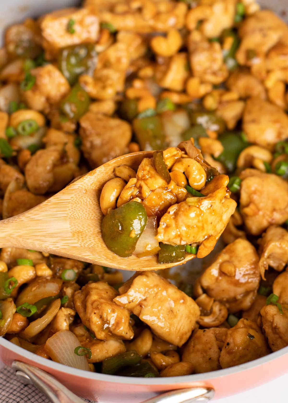 a spoonful of cashew chicken over a skillet full of cashew chicken