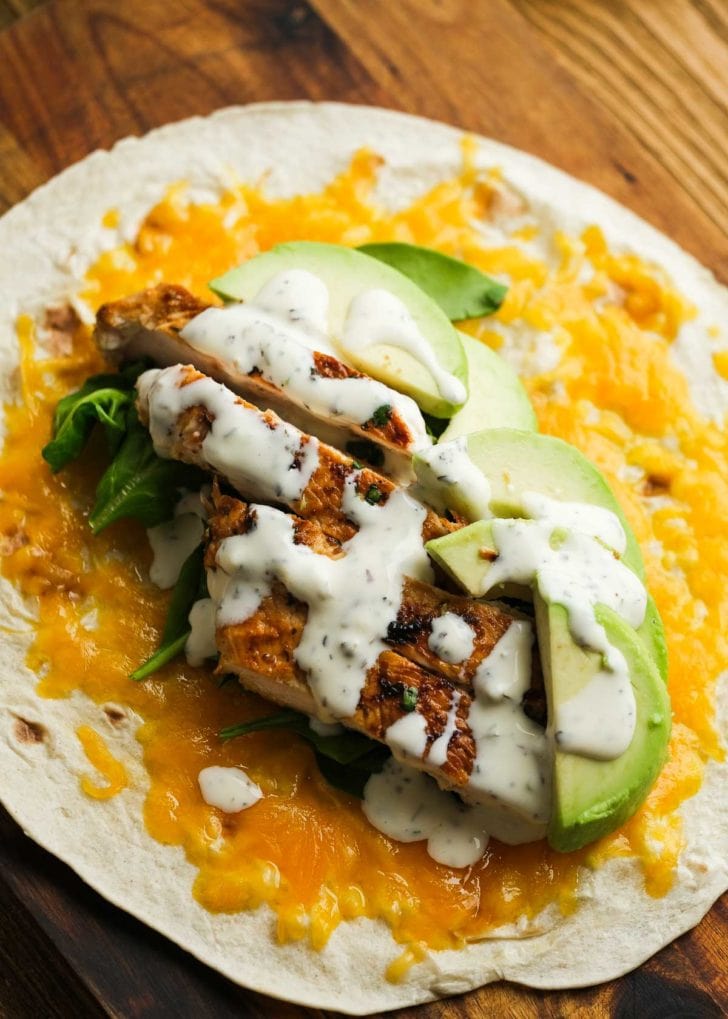 chicken avocado wrap laying open on wooden cutting board