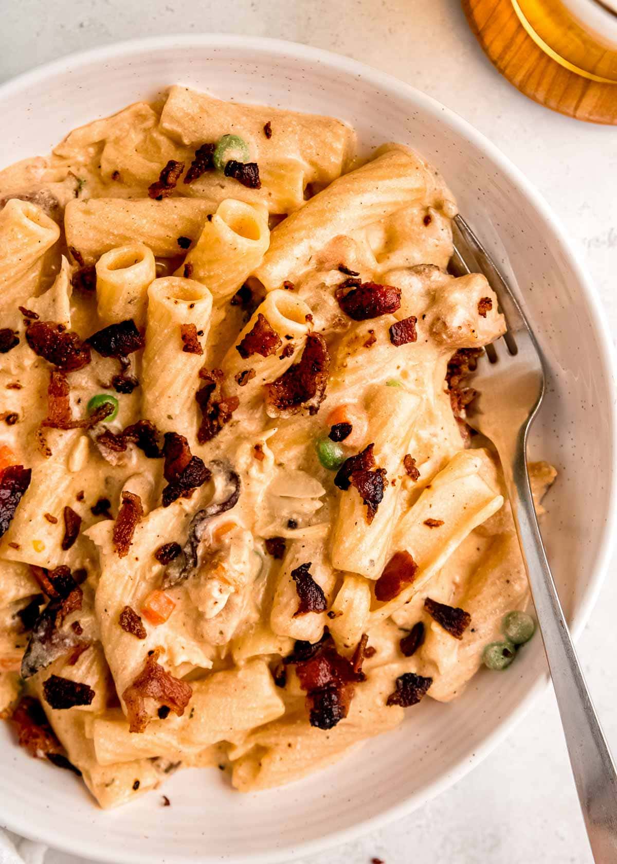 a big bowl full of chicken bacon ranch pasta with peas and carrots