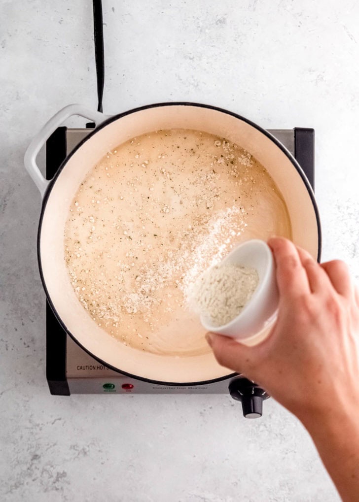 overhead image of ranch seasoning being added to dutch oven