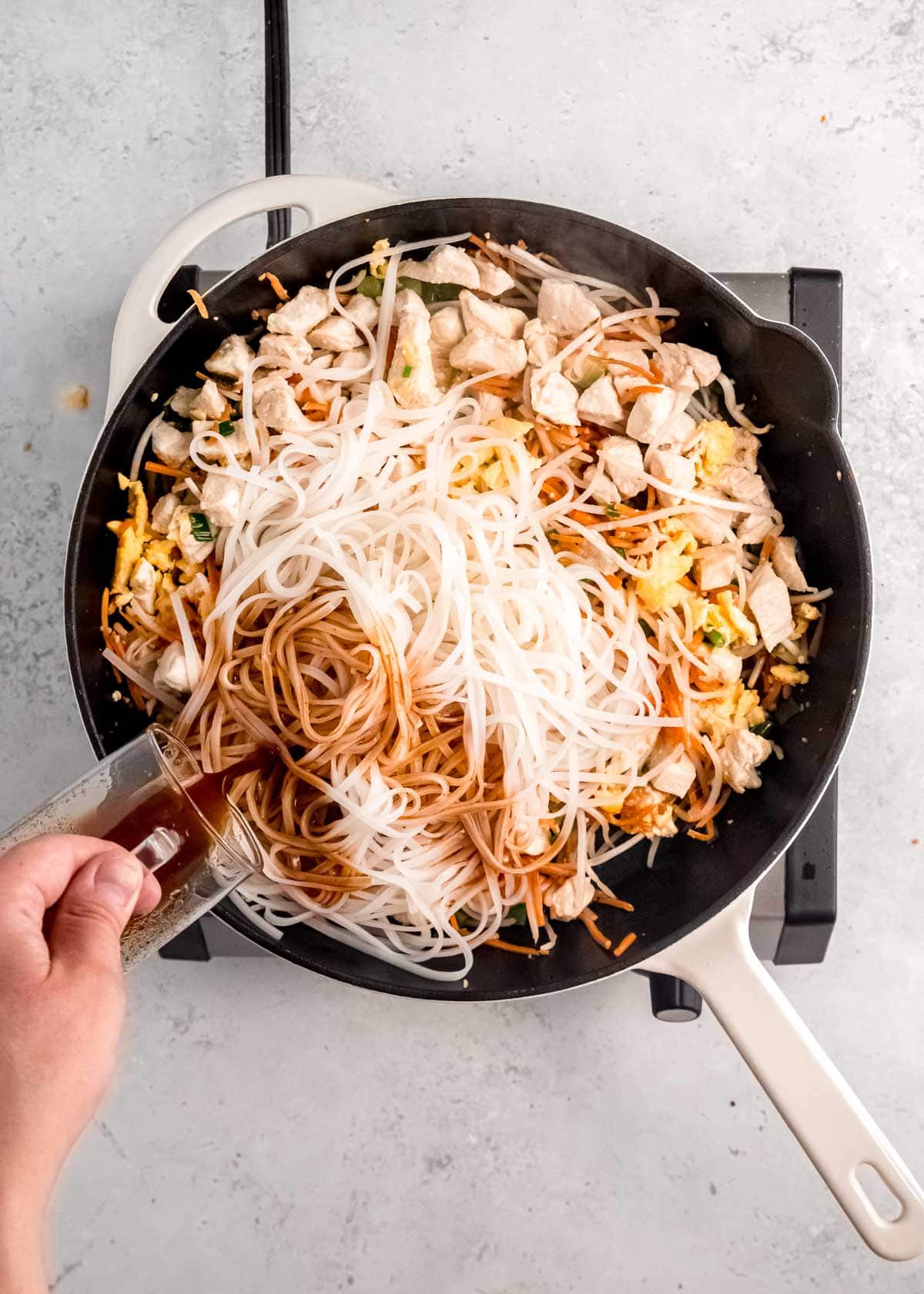 sauce being added to chicken pad thai