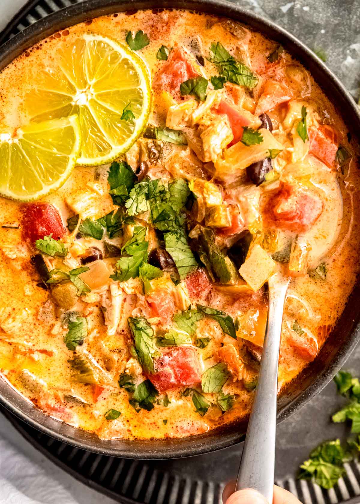 close up image of chicken poblano soup and spoon in black bowl