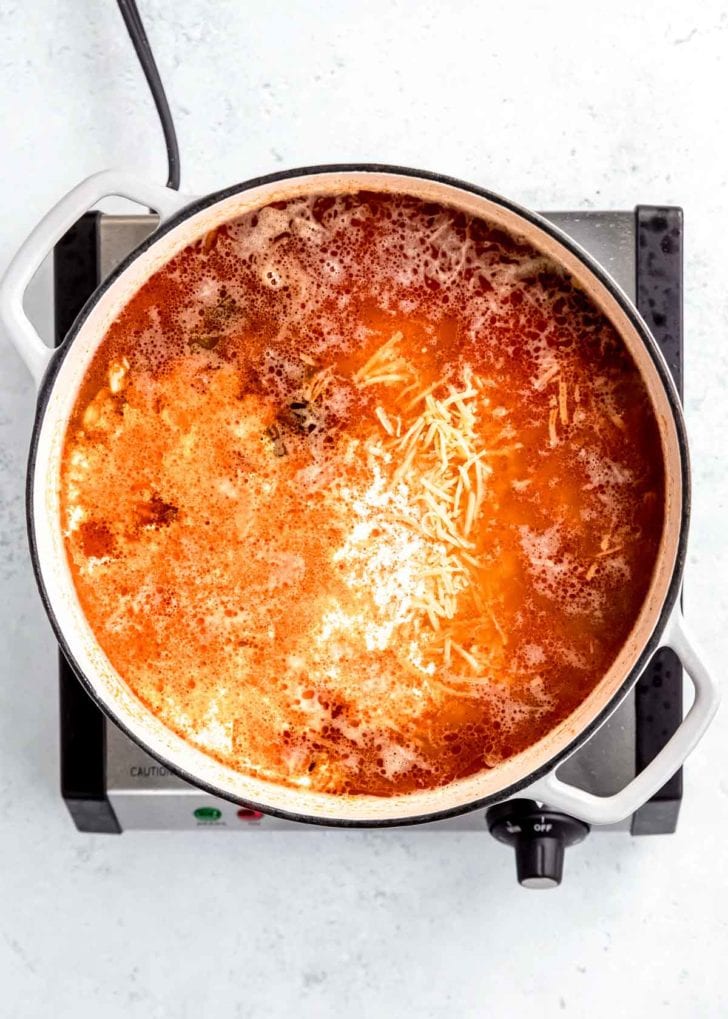 cheese being added to dutch oven with other chicken poblano soup ingredients 