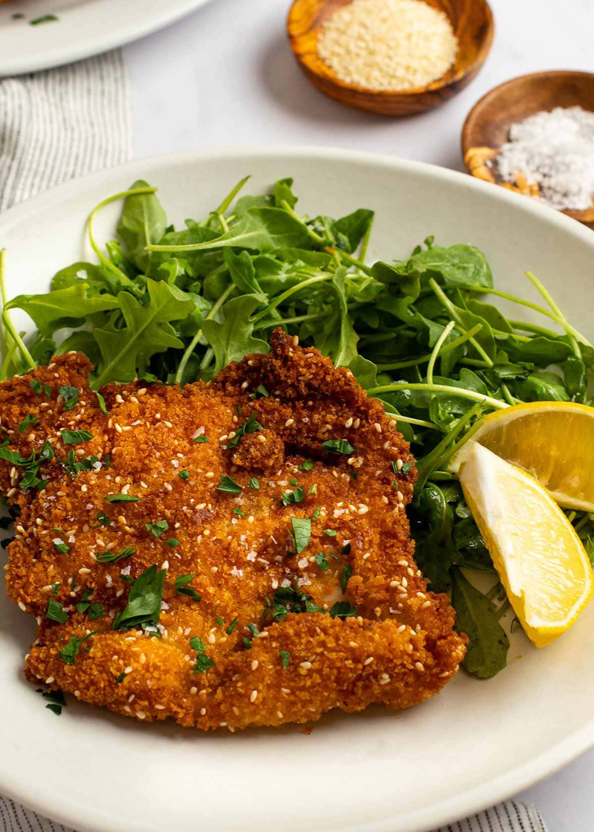 chicken schnitzel and lemon wedge on white plate 