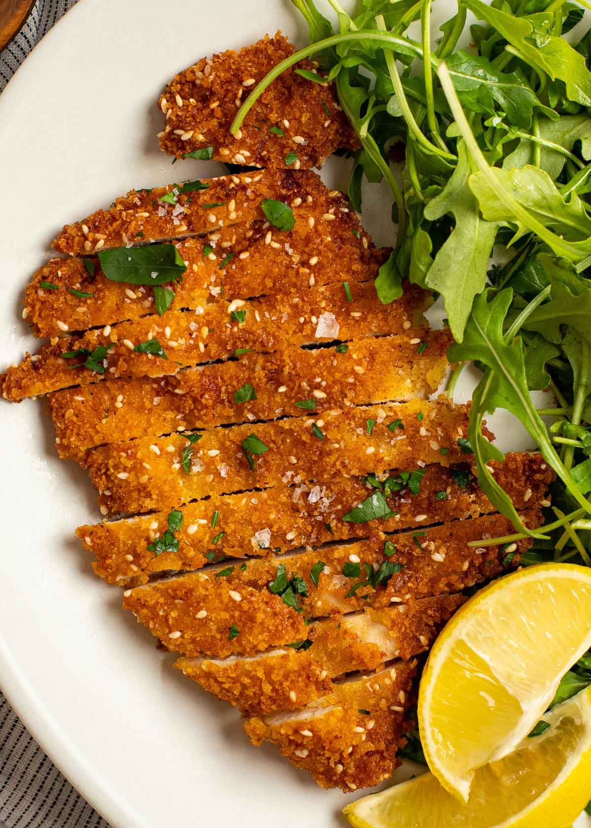 overhead image of sliced chicken schnitzel on a white plate