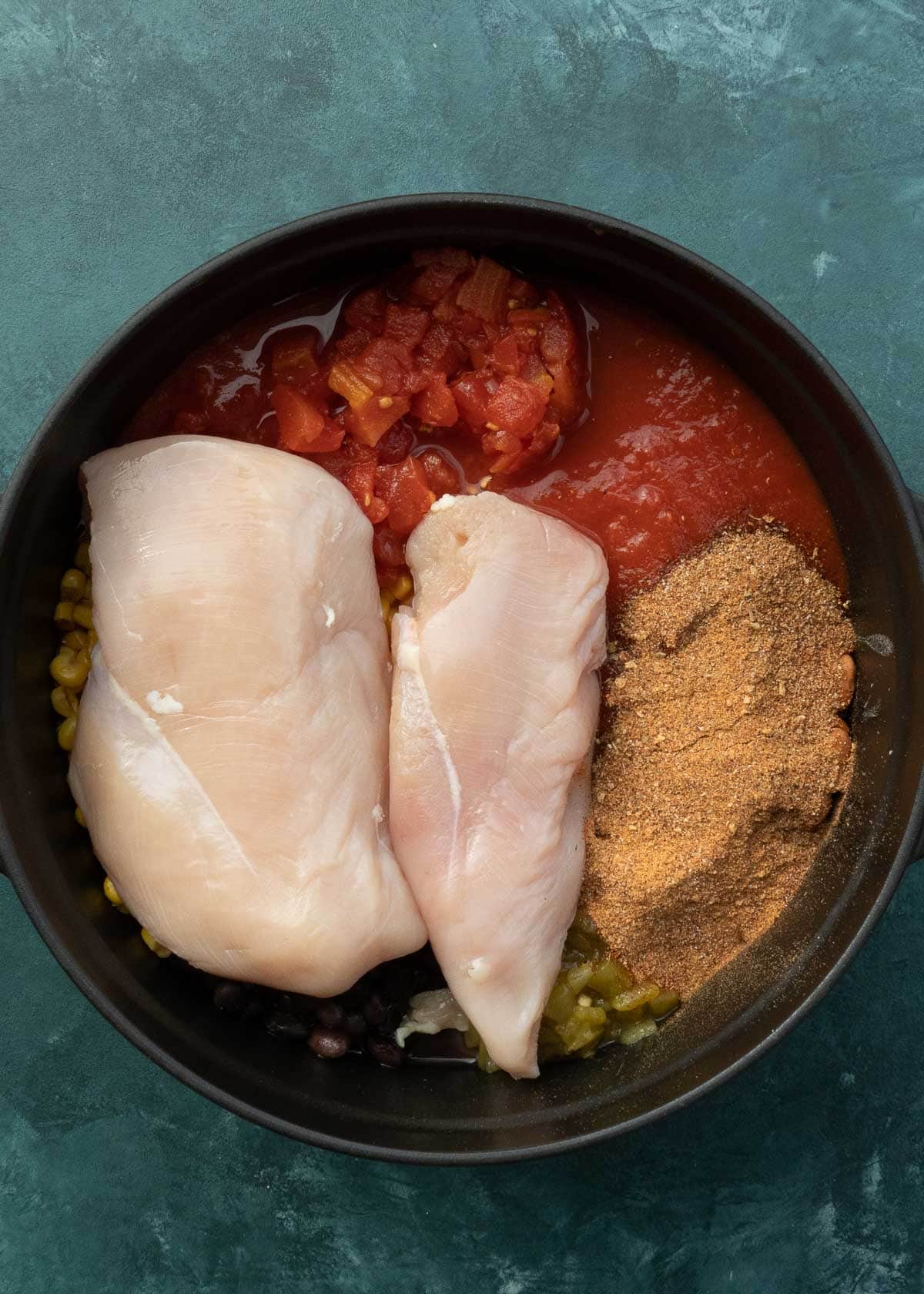 chicken, spices, and broth being added to dutch oven 