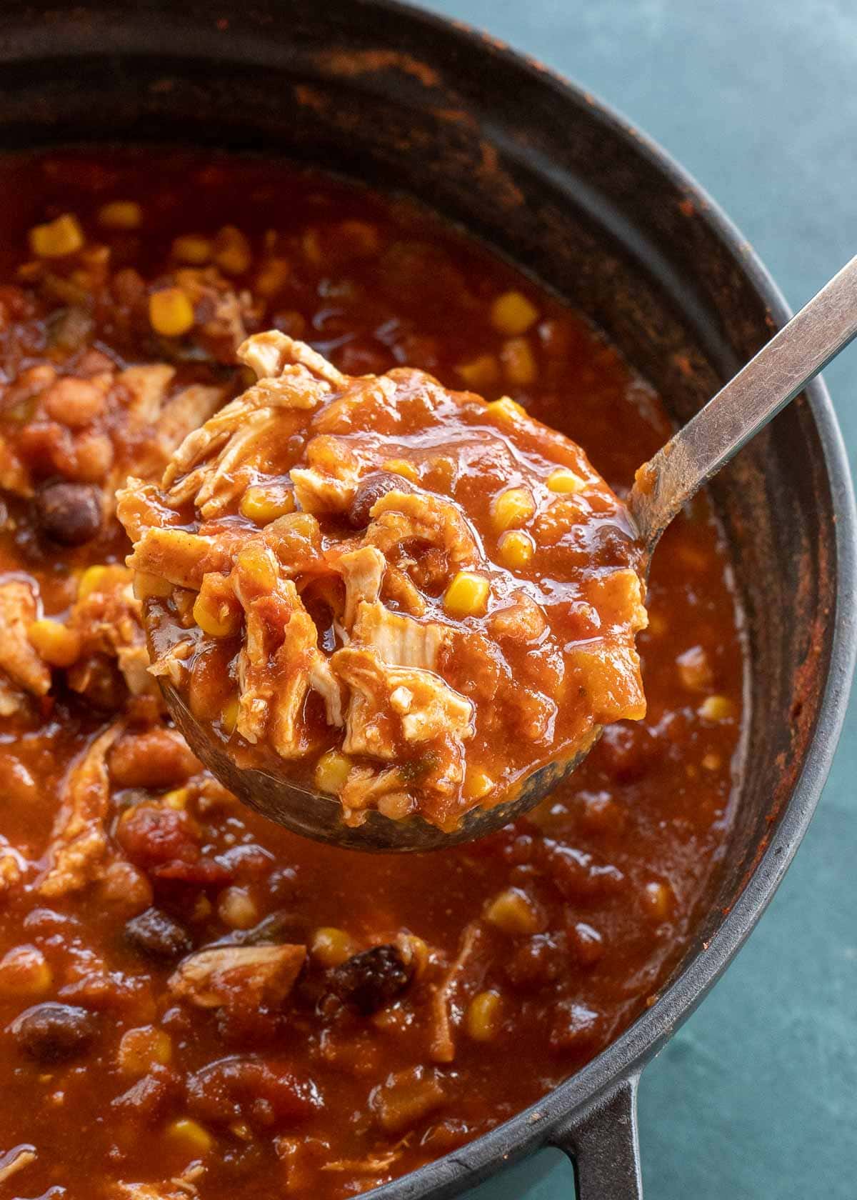 spoonful of chicken tortilla soup with dutch oven in background