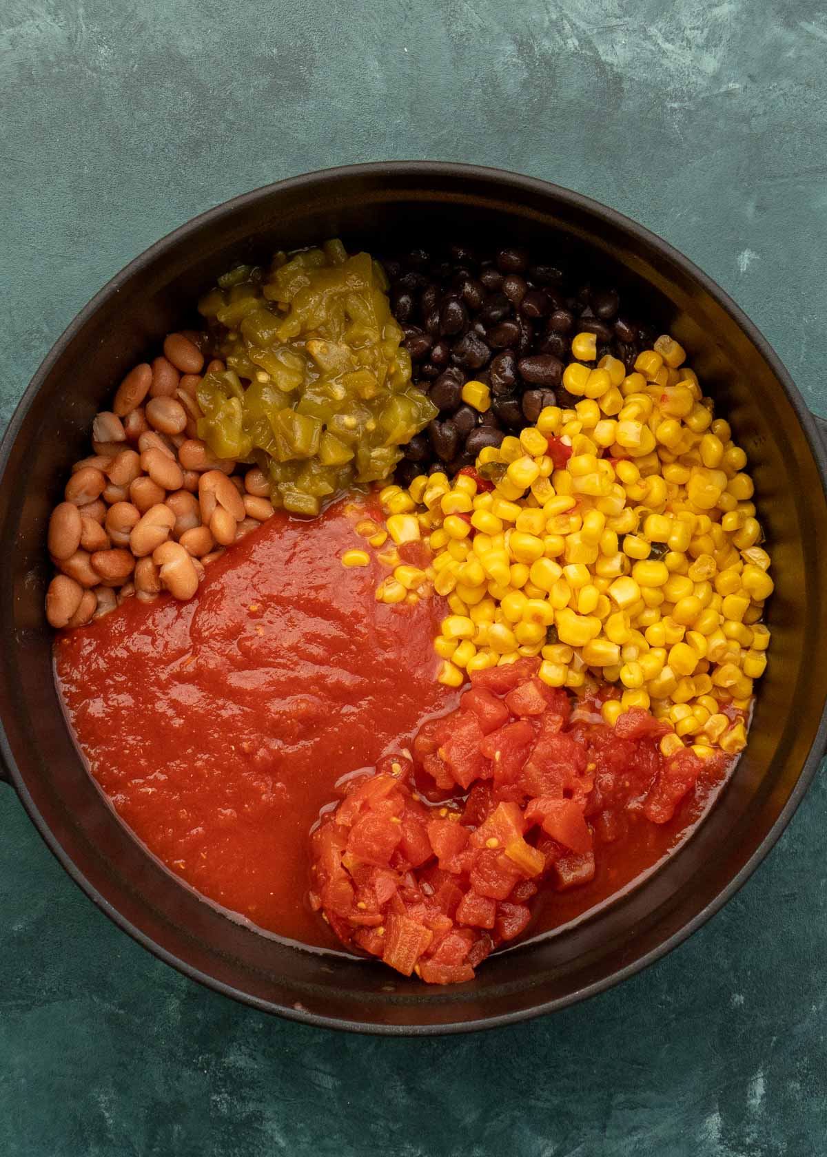 canned good ingredients being added to dutch oven for chicken tortilla soup