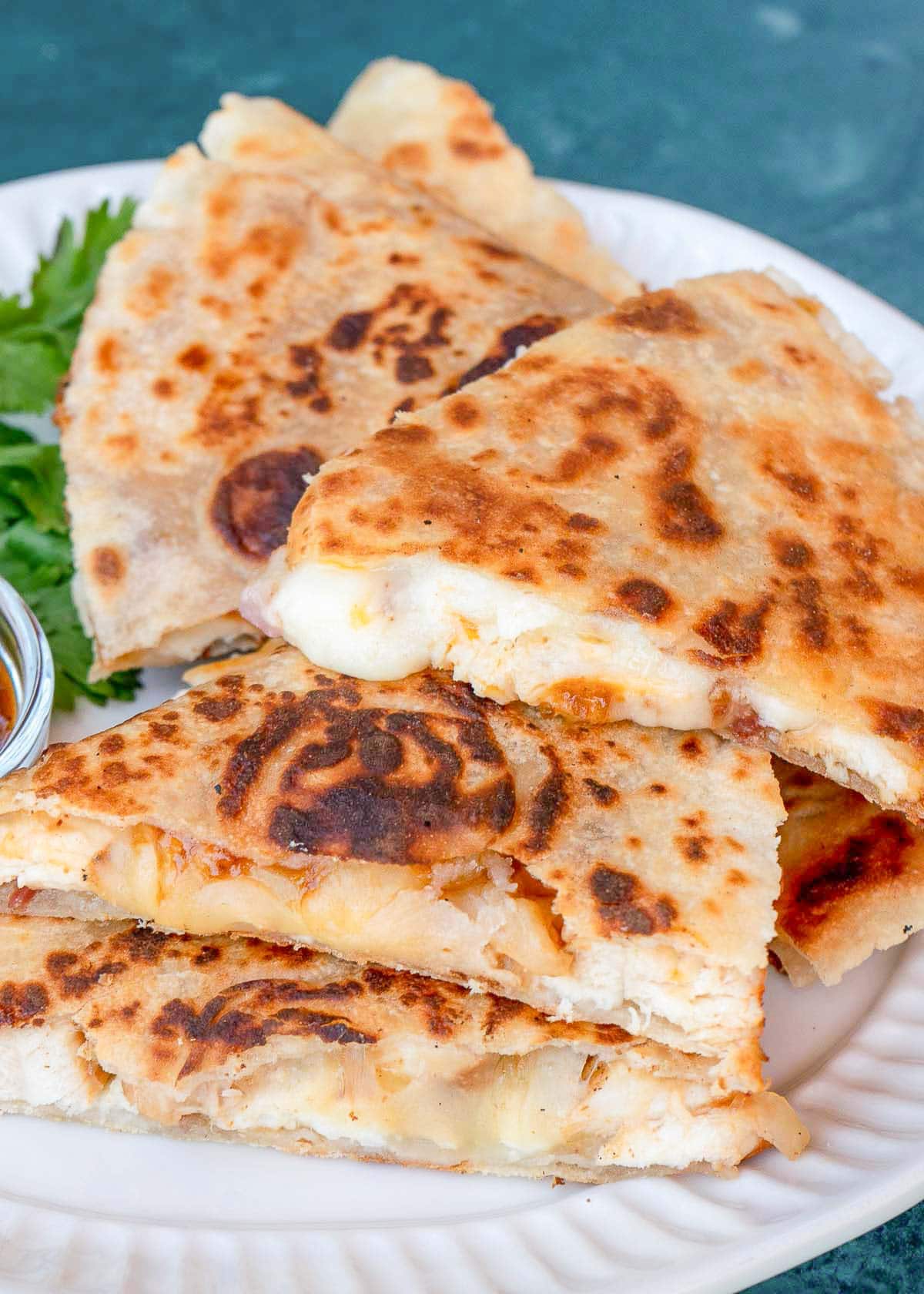 close up image of bbq chicken quesadillas stacked on a white plate 