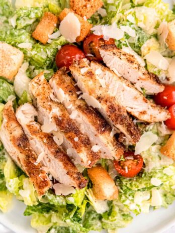 close up image of chicken caesar salad on white plate