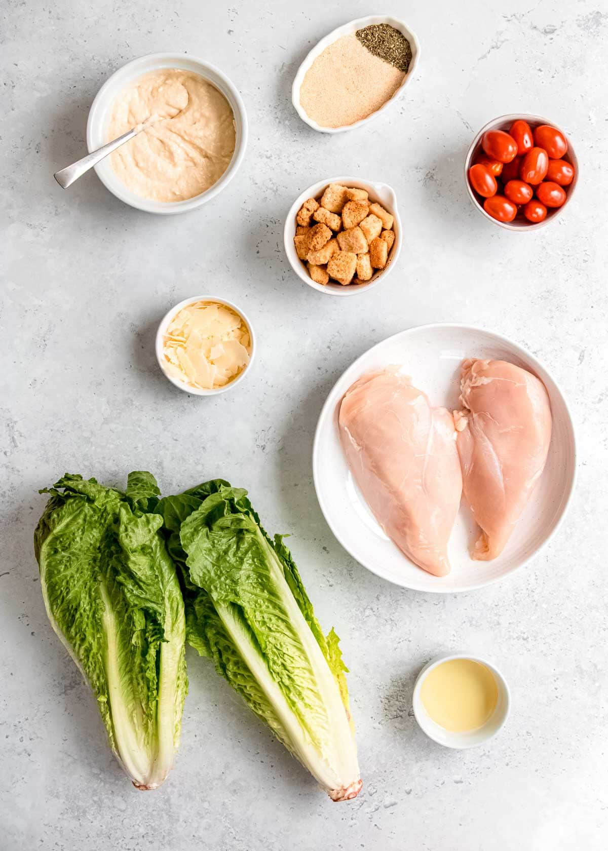chicken caesar salad ingredients on a white table