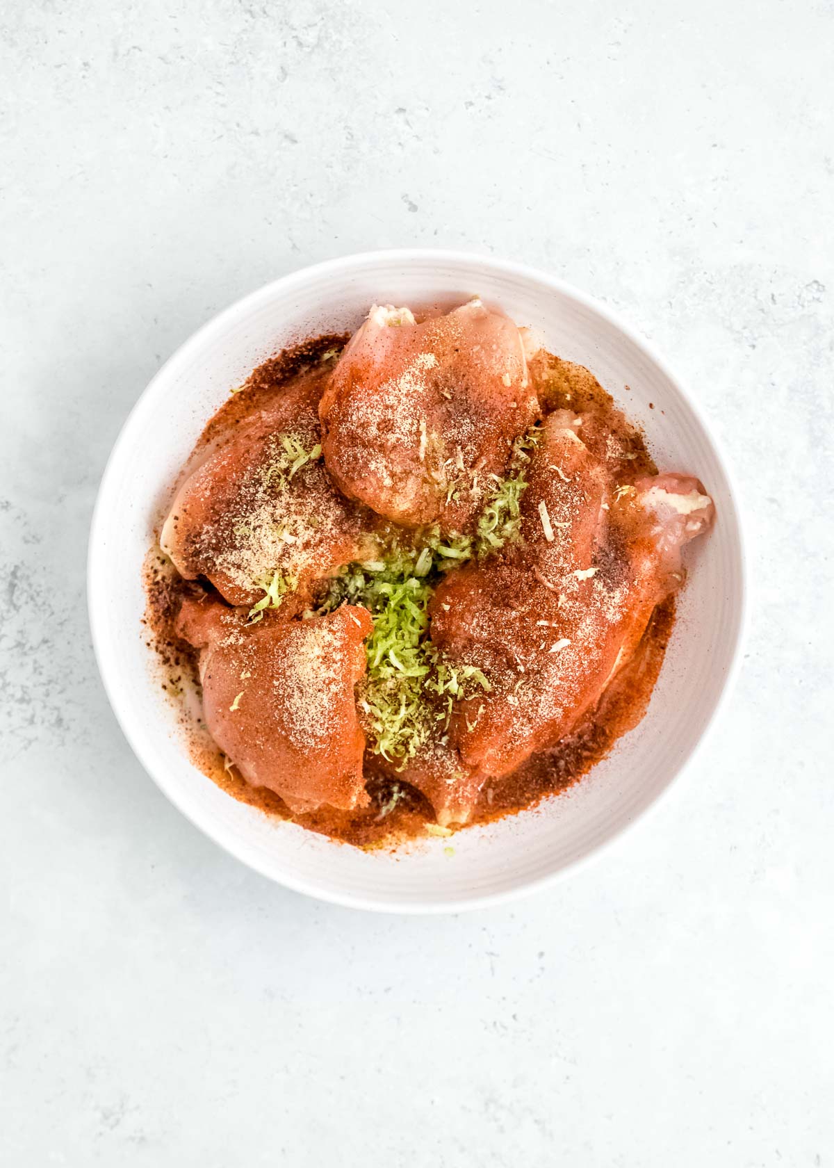 chicken marinating in white bowl