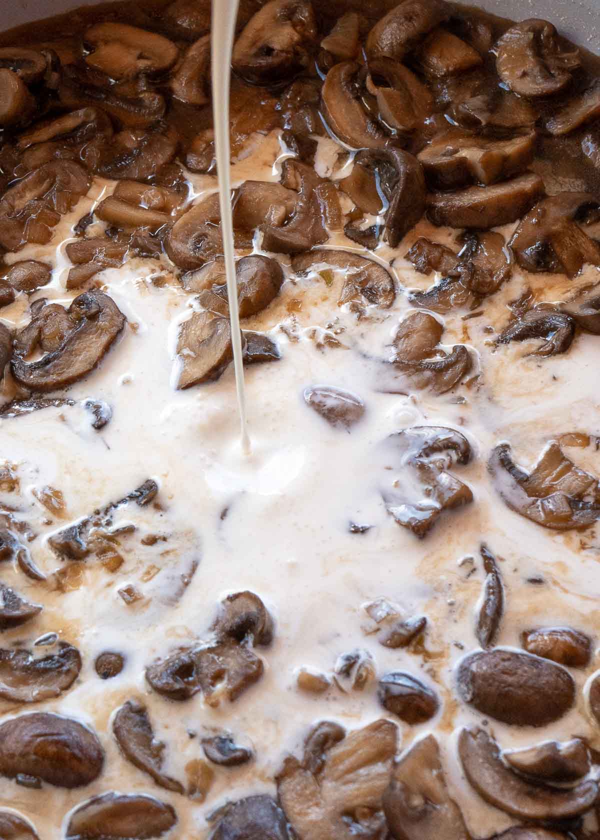 cream being added to mushrooms in skillet