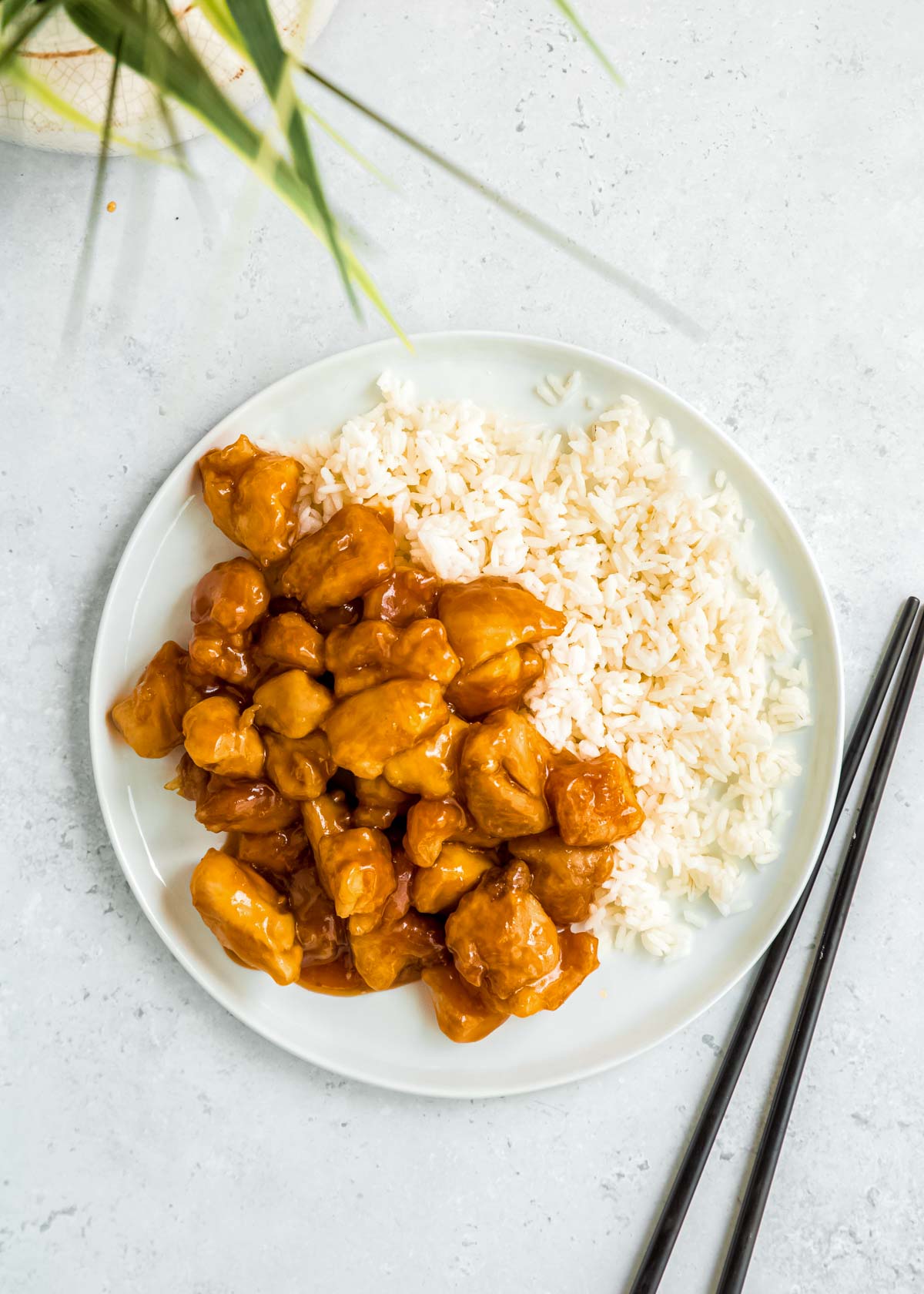 overhead image of orange chicken and rice on a white plate 