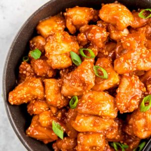 close up overhead image of sesame chicken in black bowl