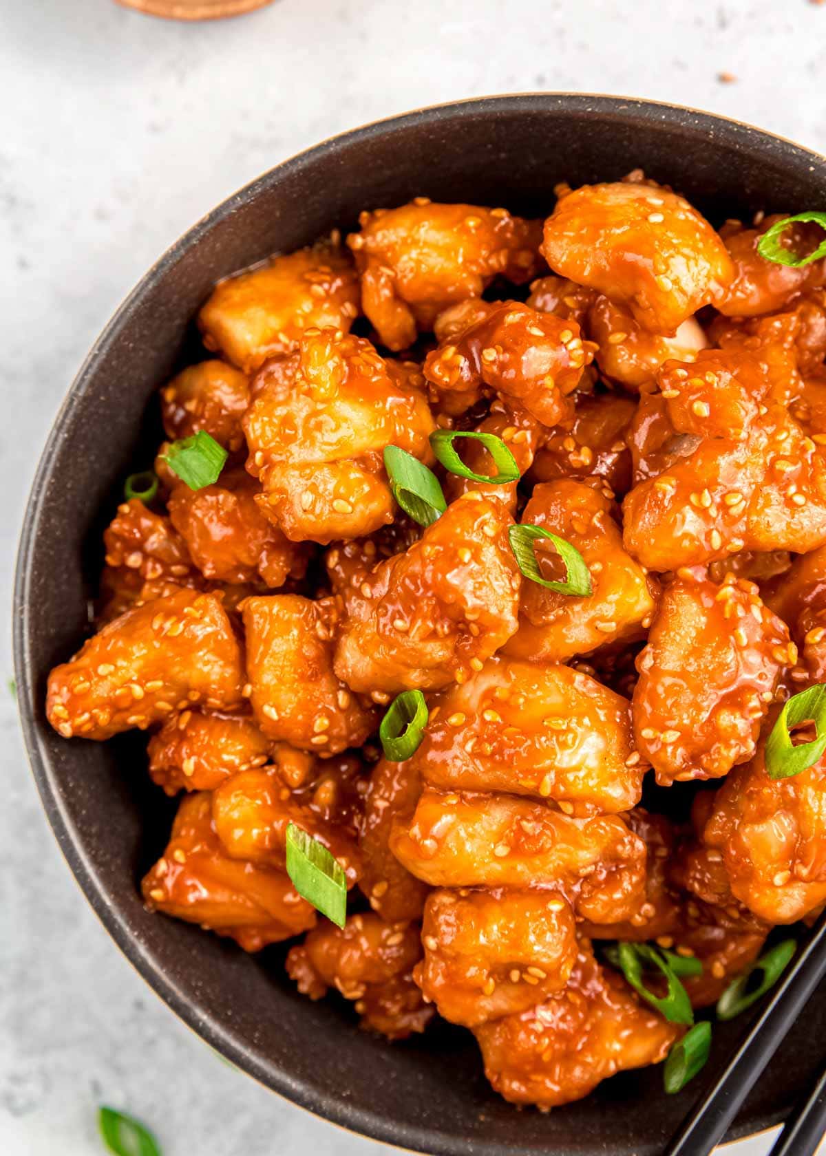 close up overhead image of sesame chicken in black bowl