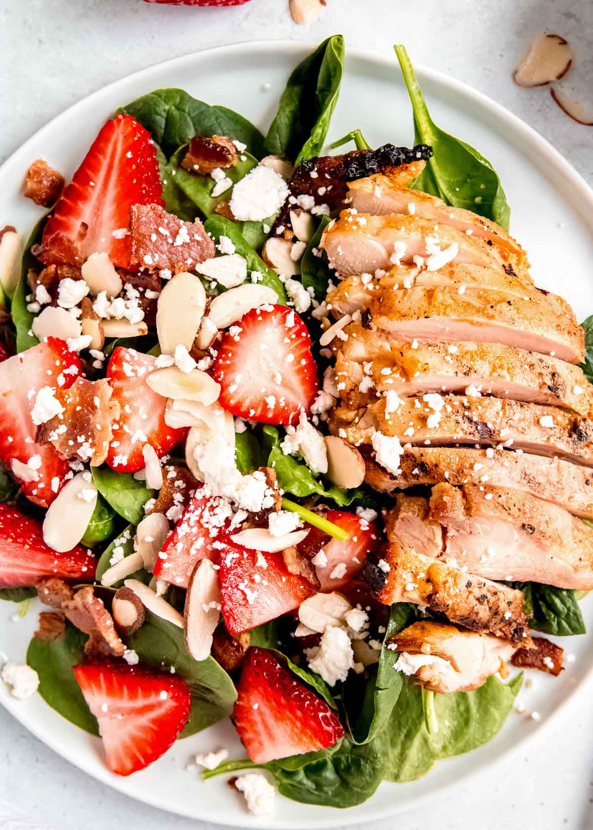 close up, overhead image of strawberry spinach chicken salad on white plate 