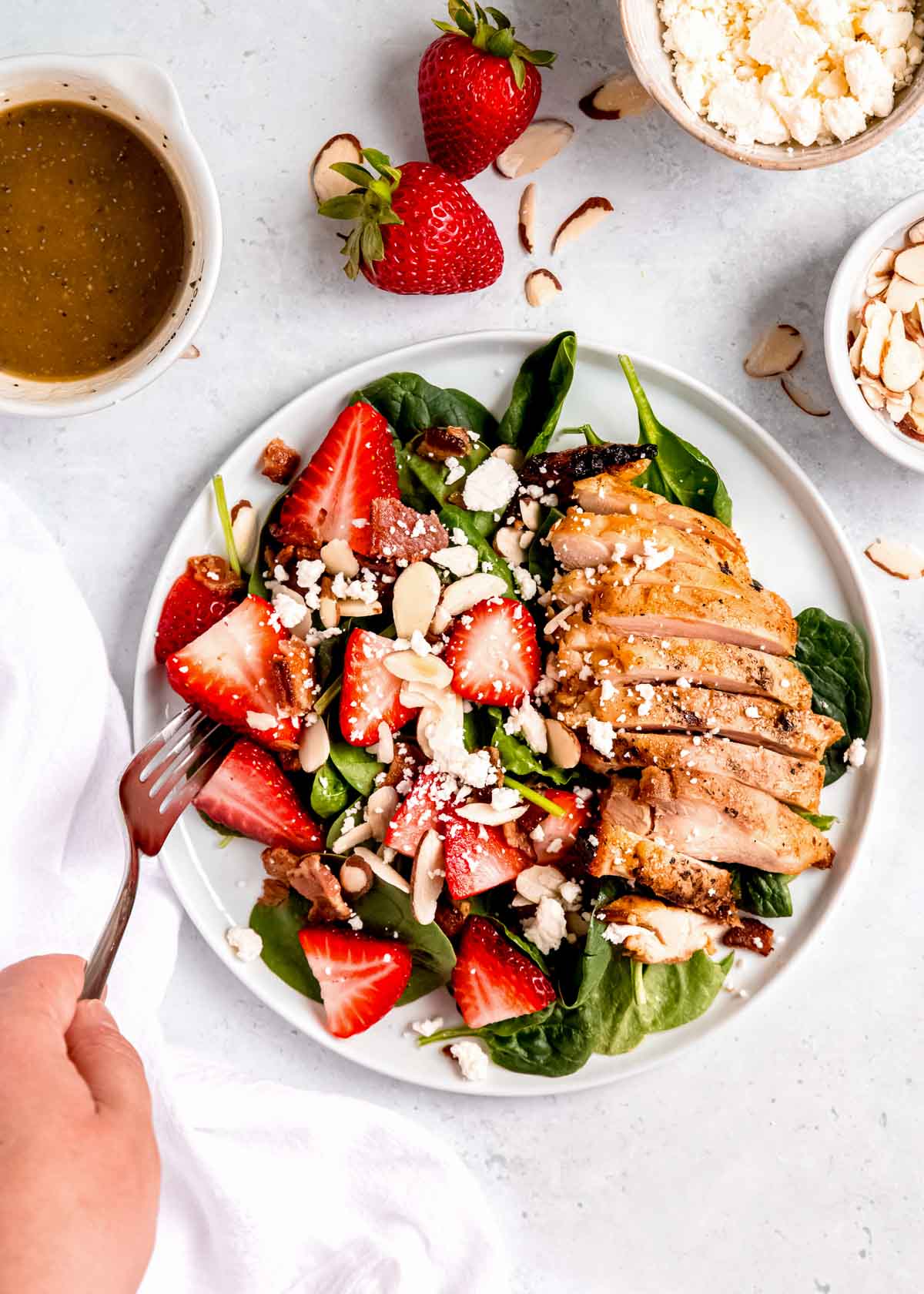 overhead image of strawberry spinach chicken salad and fork on white plate