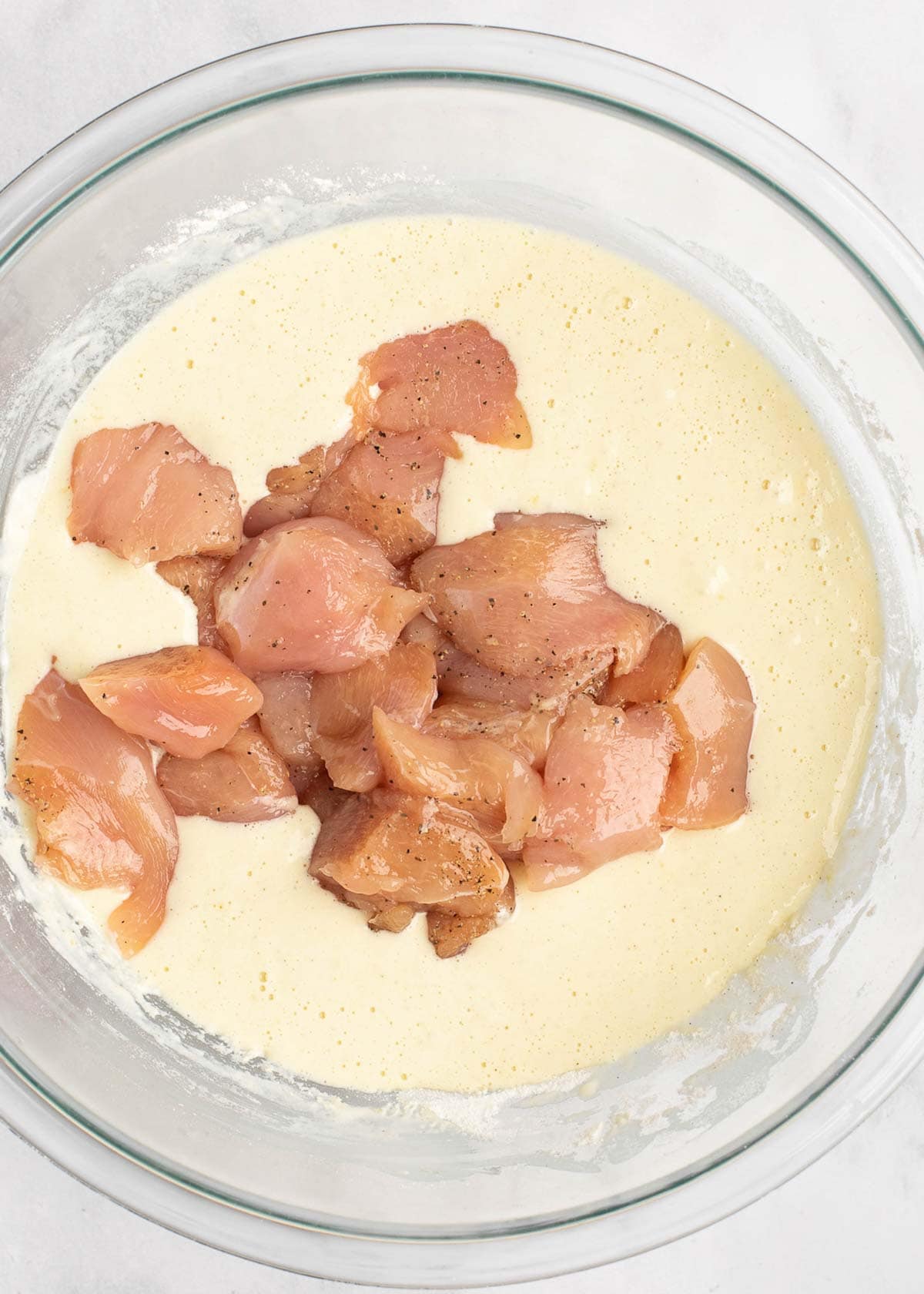 raw chicken in batter in mixing bowl