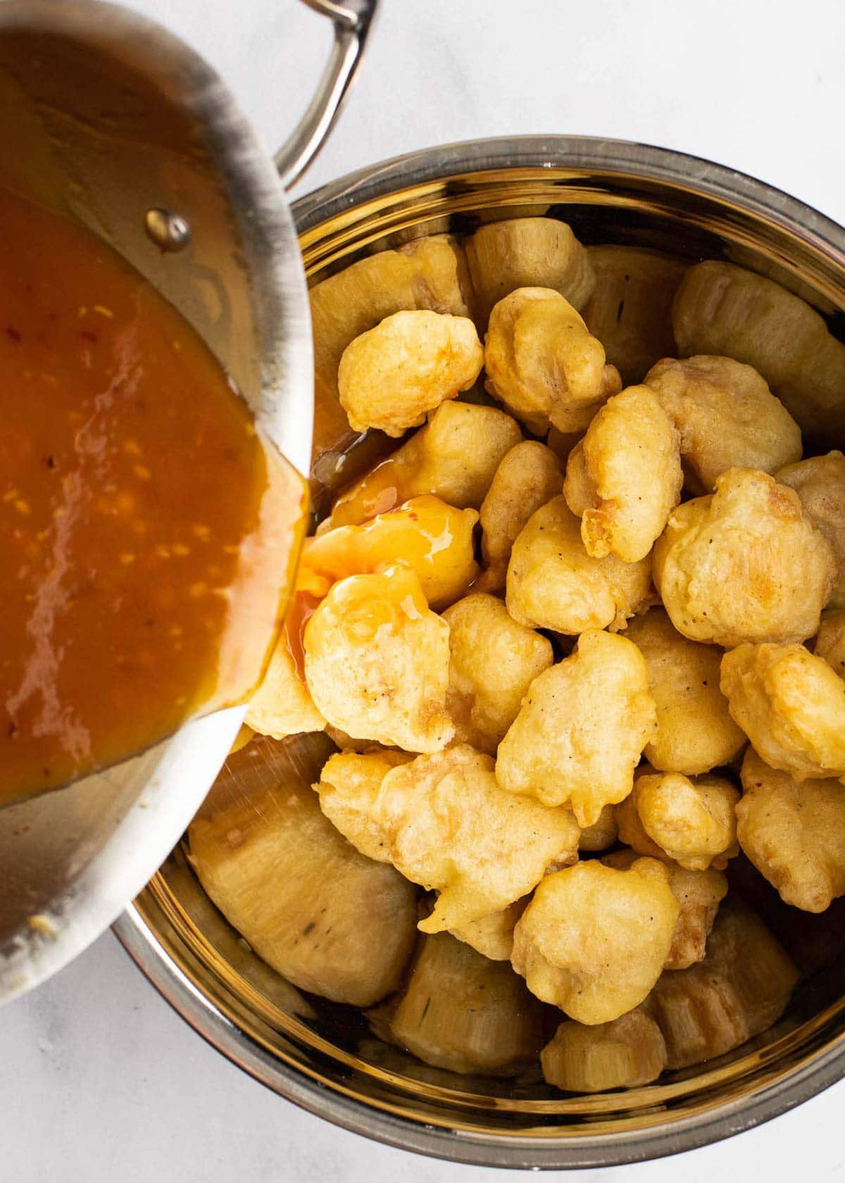 chicken being tossed in sweet and sour sauce