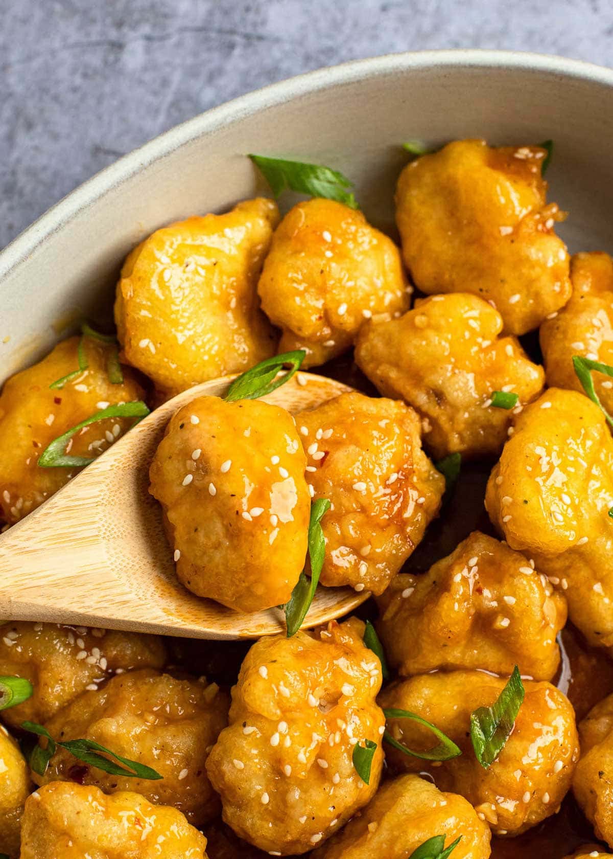 a wooden spoon with sticky sweet and sour sauced fried chicken