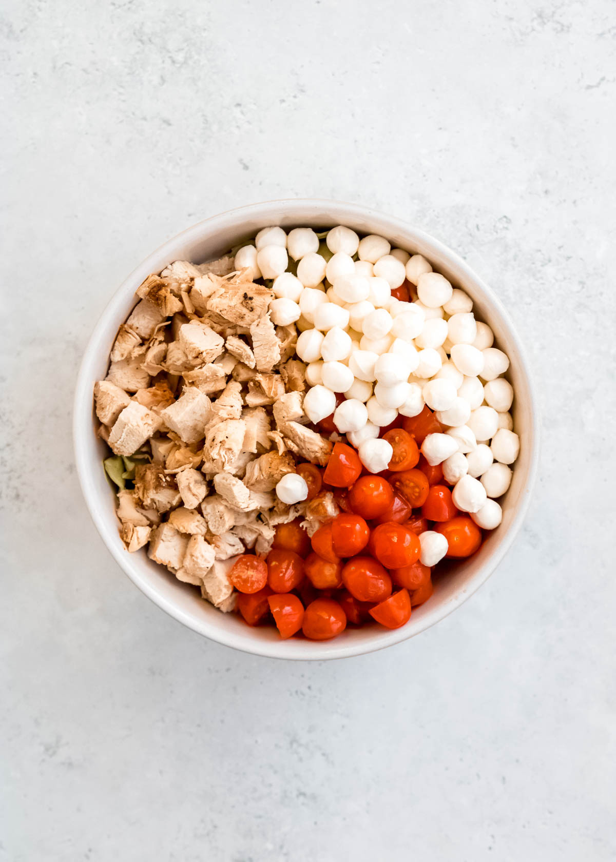 tortellini pasta salad ingredients combined in a white bowl