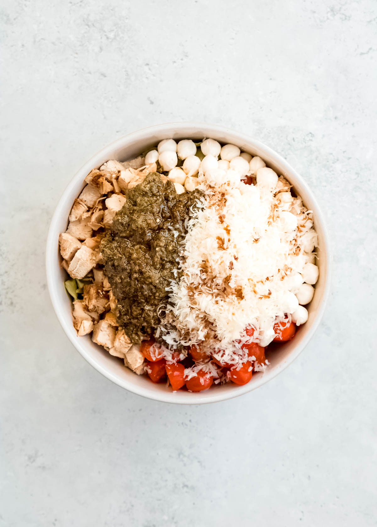 dressing ingredients being added to tortellini pasta salad in white bowl