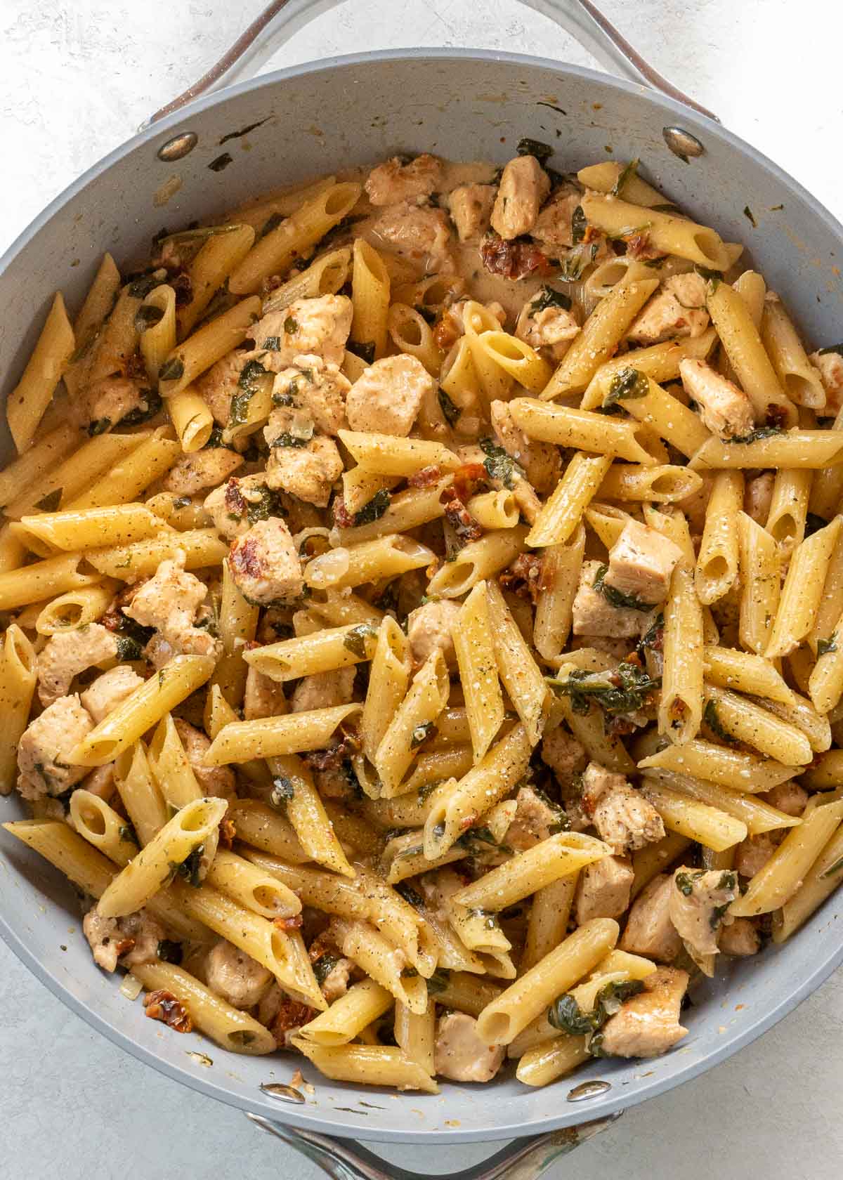 overhead image of tuscan chicken pasta in gray skillet