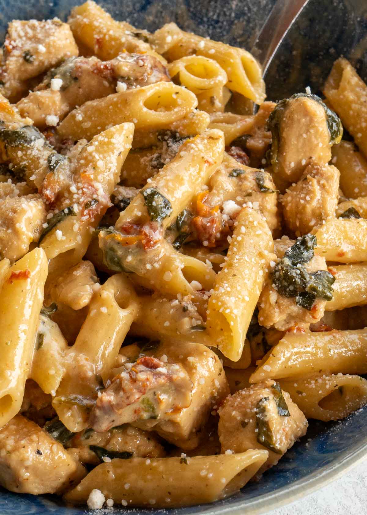 close image of tuscan chicken pasta in blue bowl