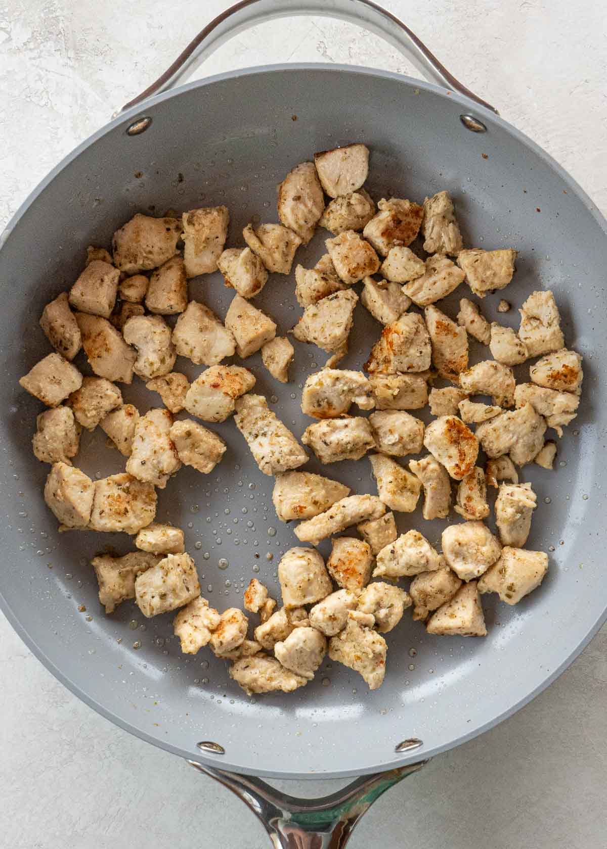 chicken being cooked in gray skillet