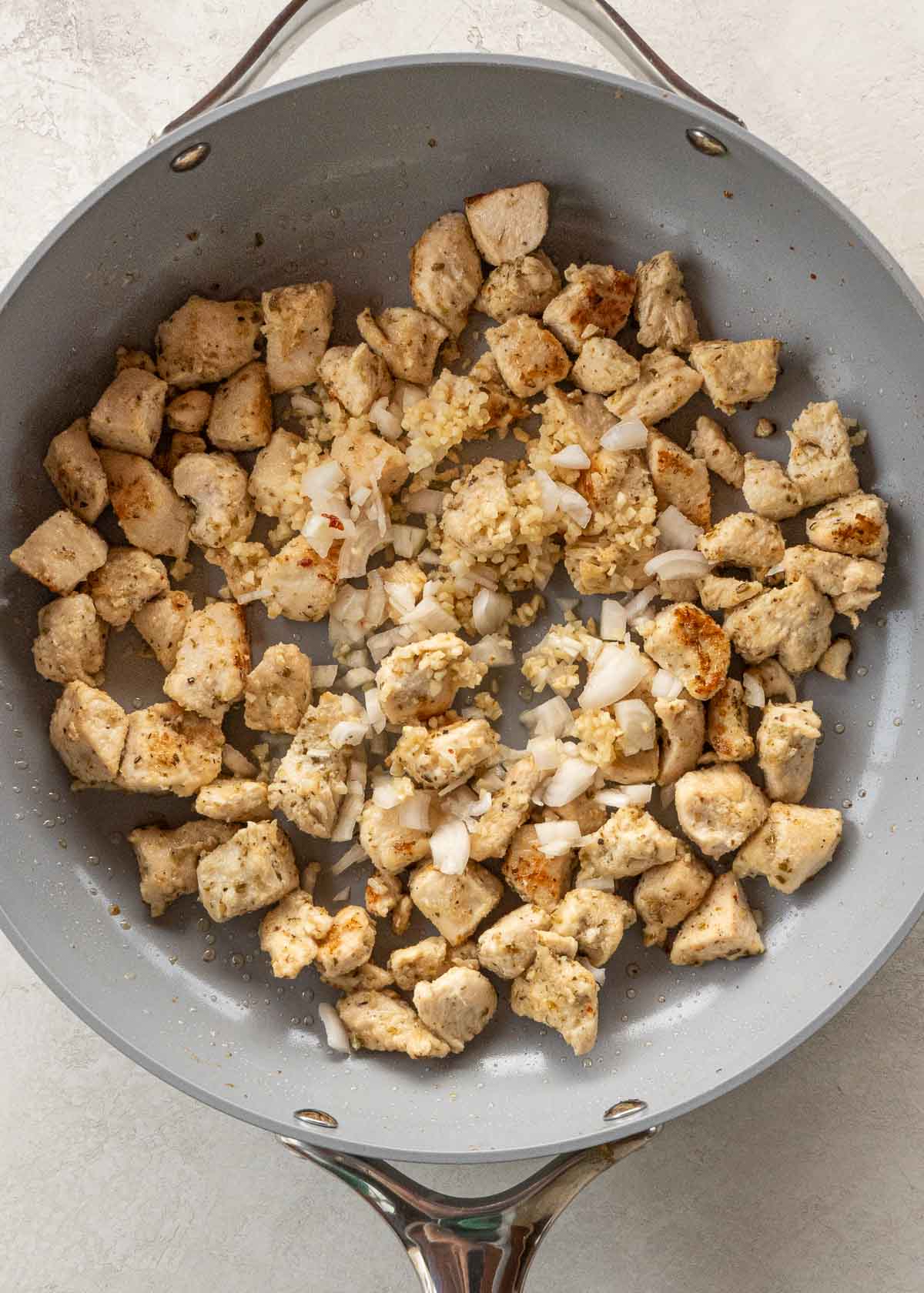 garlic, shallots, and chicken in a gray skillet