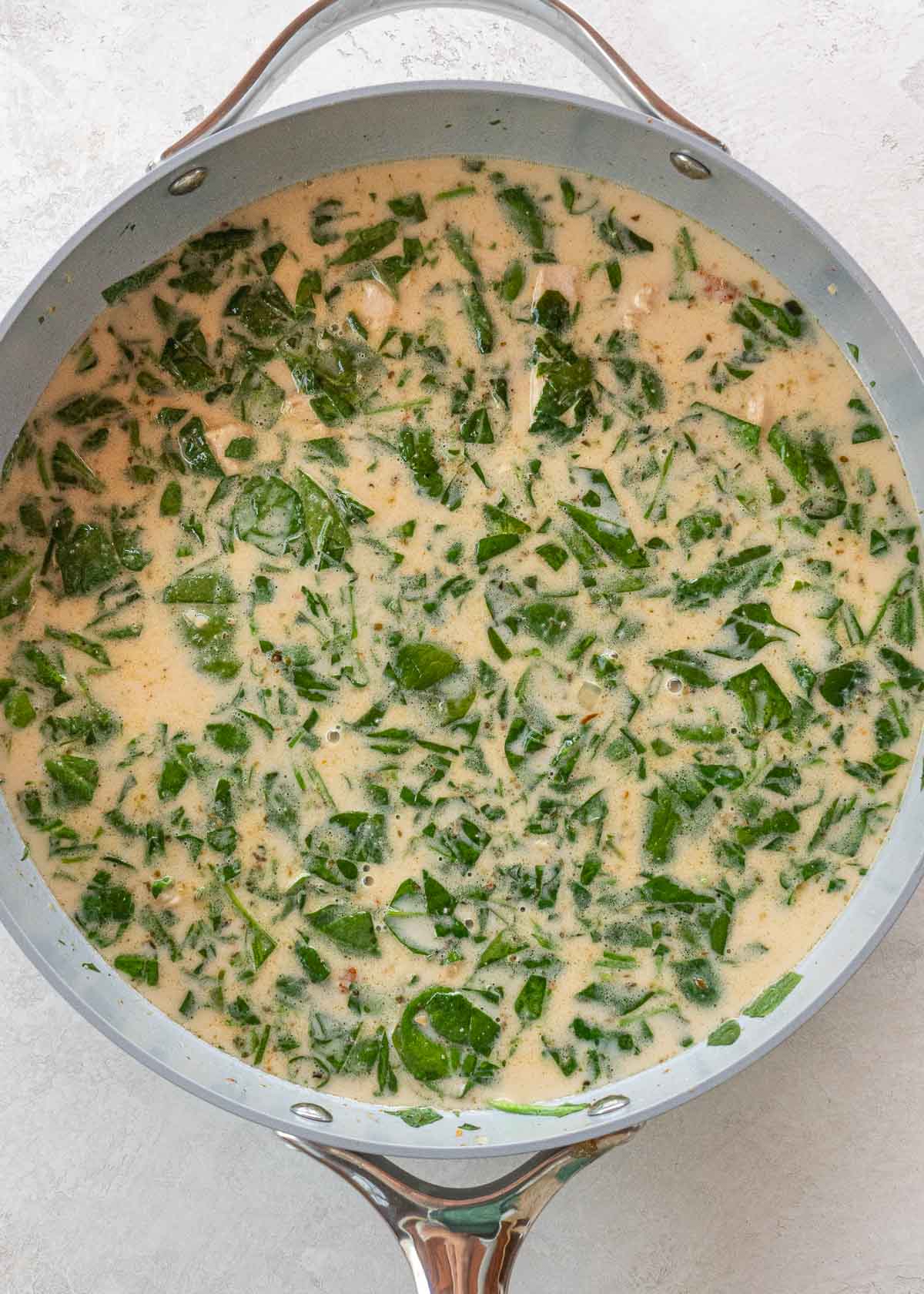 chicken, veggies, heavy cream, and chicken broth in gray skillet