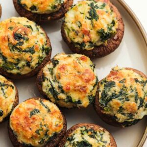 Delicious crab stuffed mushrooms with bacon, spinach, and cheese on a white plate