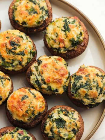 Delicious crab stuffed mushrooms with bacon, spinach, and cheese on a white plate