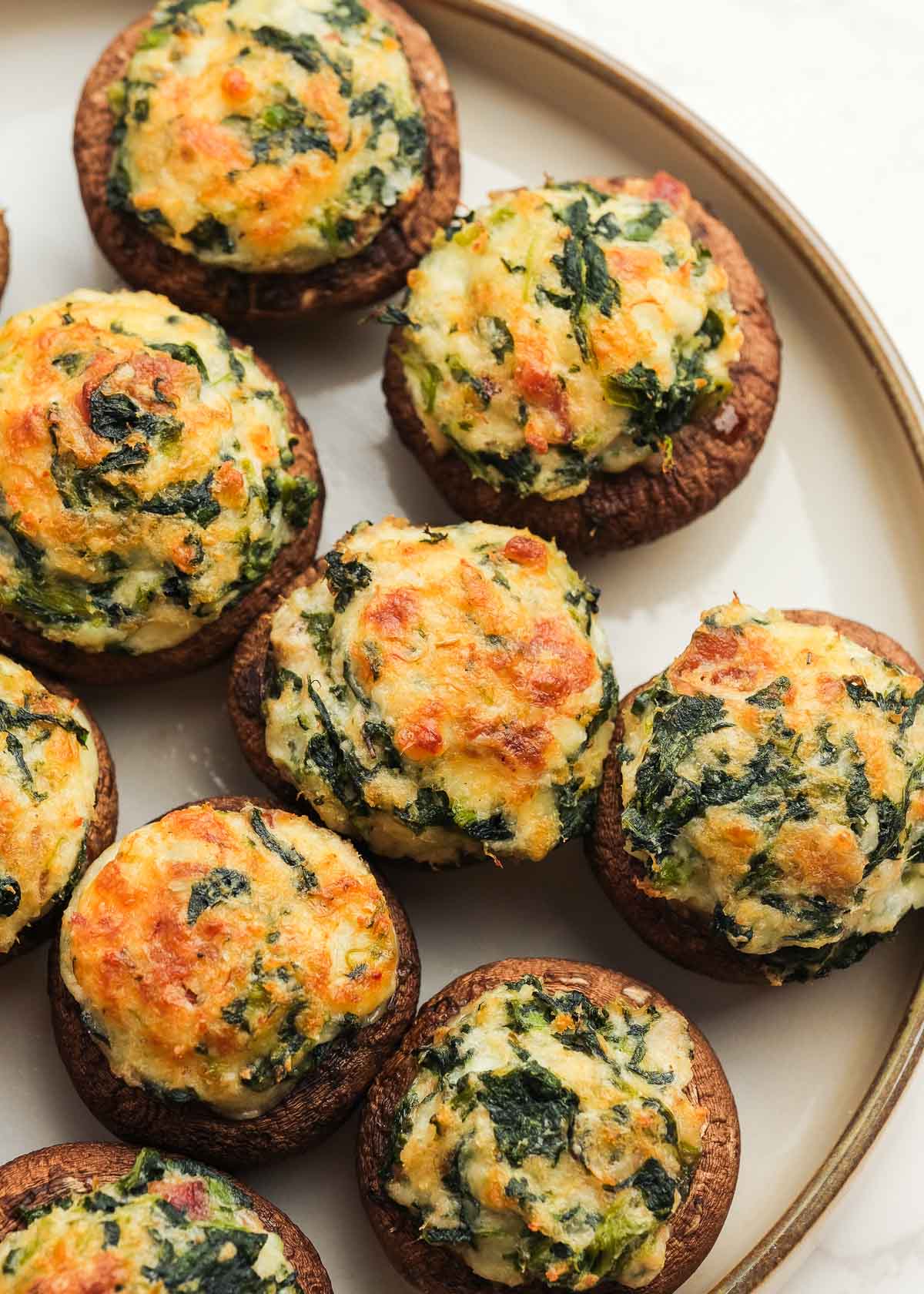 Delicious crab stuffed mushrooms with bacon, spinach, and cheese on a white plate