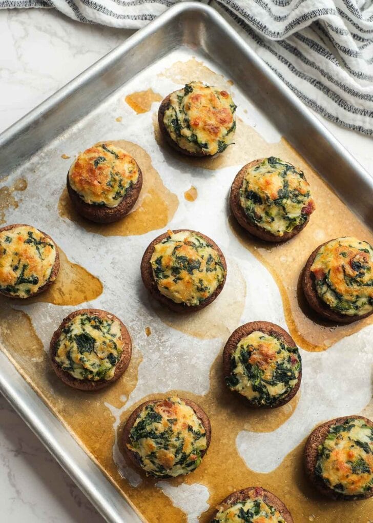 an overhead shot showing twelve crab and bacon stuffed mushrooms on a sheet pan