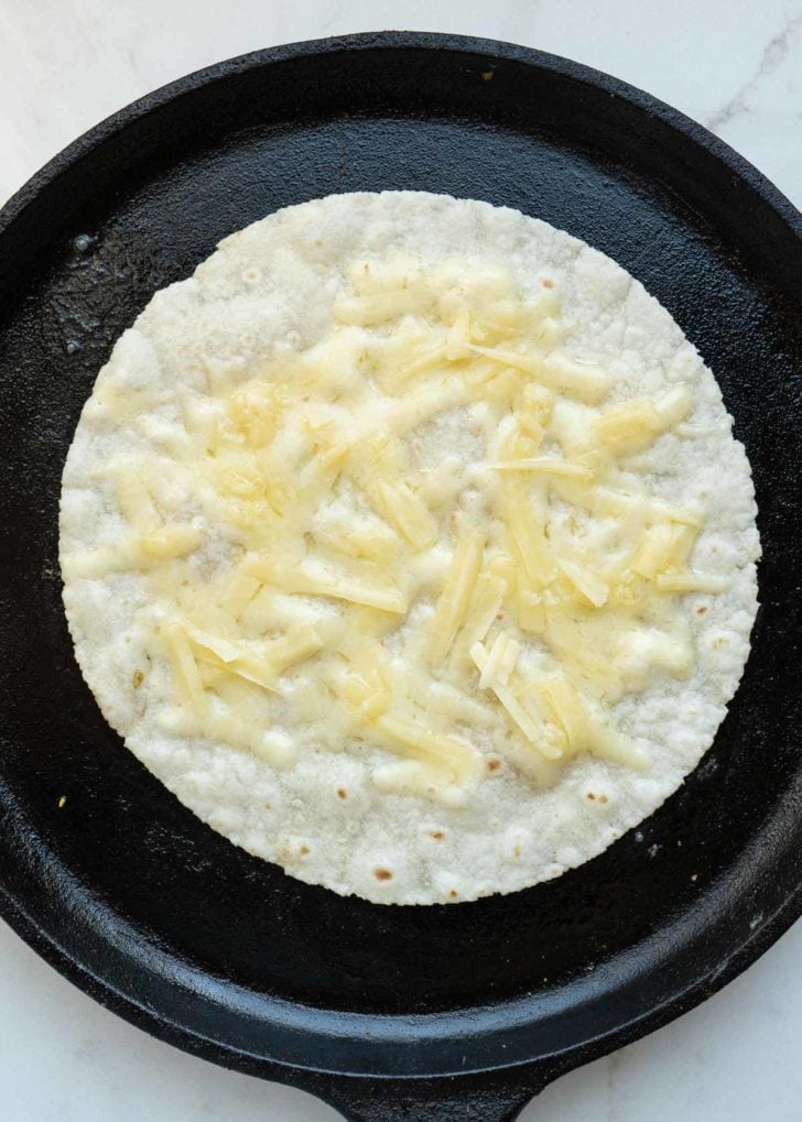 a tortilla in with melted cheddar