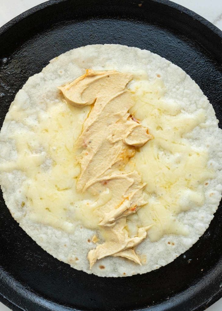 a tortilla with melted cheddar and hummus