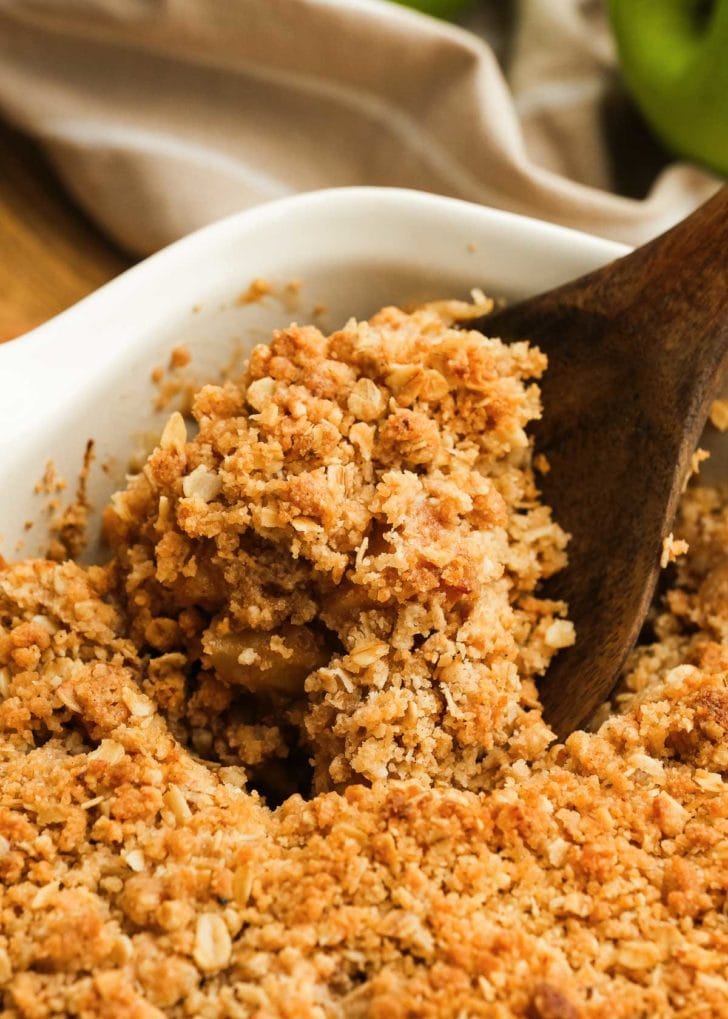 close up image of a wooden spoon and apple crisp