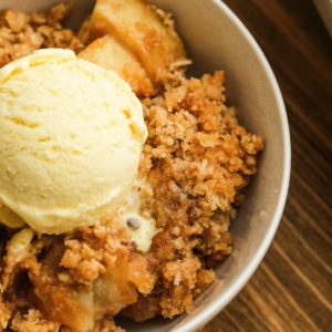 close up image of apple crisp and ice cream in white bowl
