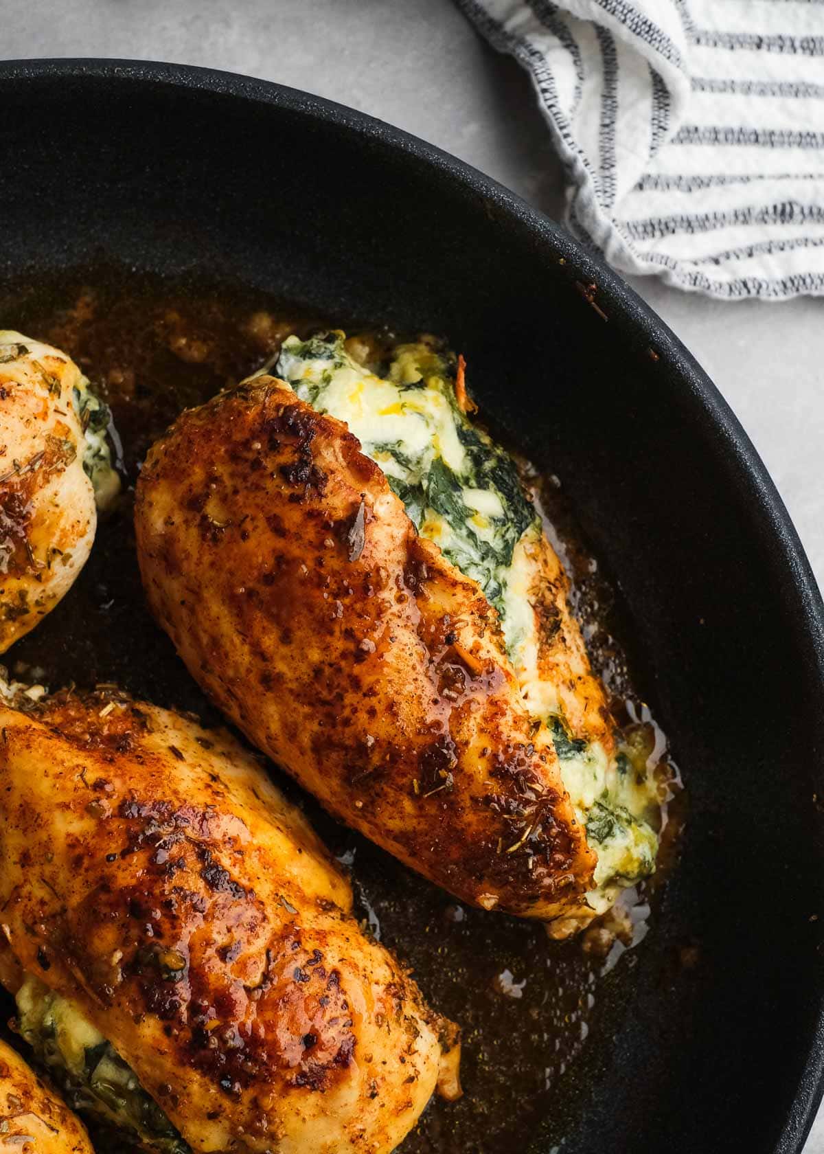 a skillet with spinach stuffed chicken that has been cooked 