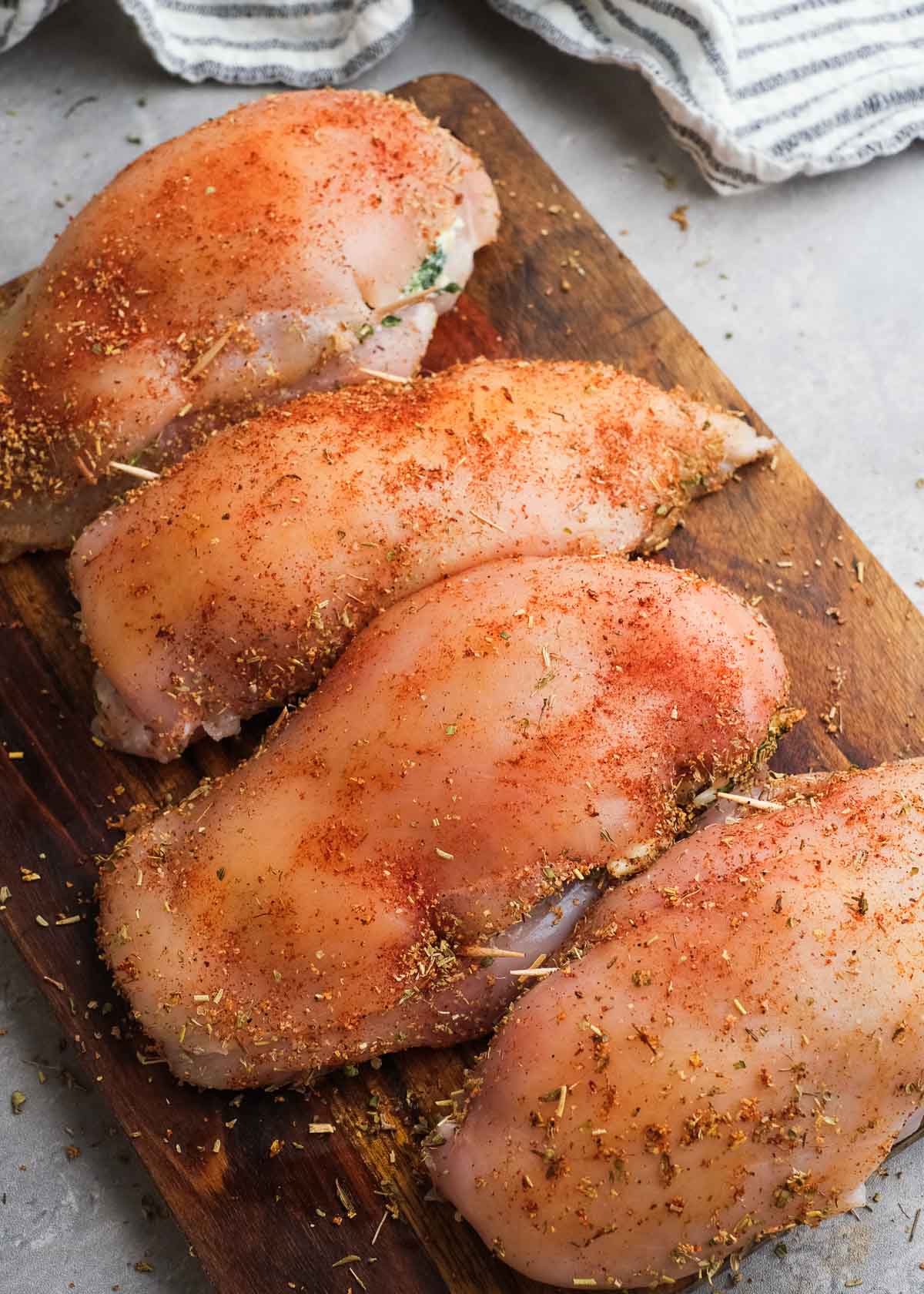 seasoned stuffed chicken uncooked on a cutting board