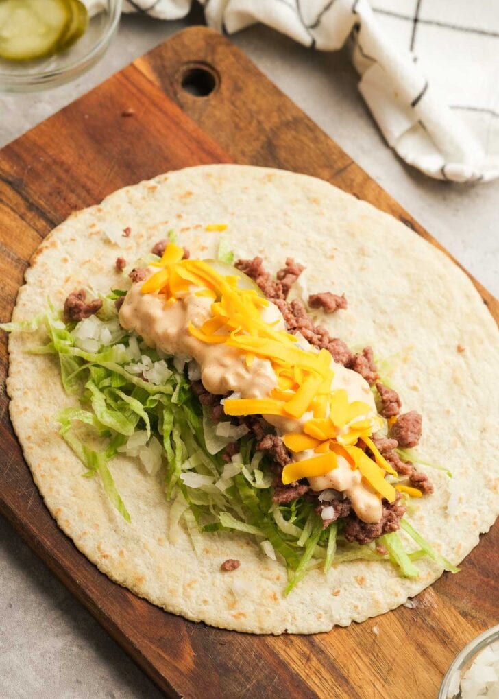 overhead shot of opened tortilla topped with beef, cheese, lettuce, and sauce for a big mac wrap